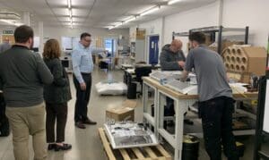 VeriVide staff giving a tour inside the Leicester facility, observing assembly work at a production bench.