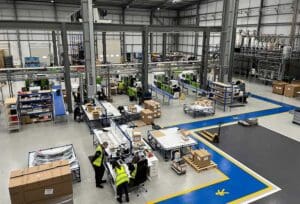 Opus' modern manufacturing facility with machinery, workstations and staff in high‑visibility vests working on the factory floor.